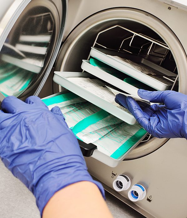 doctor's hands in rubber gloves taking sterile instruments out of an autoclave. close-up of a doctor's hands in rubber gloves taking sterile instruments out of an autoclave.